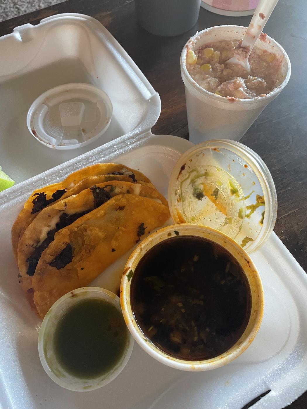 A gordita with a cup of consomme and a drink