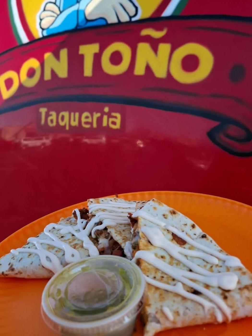 Tacos in front of the truck's painted Taqueria lettering